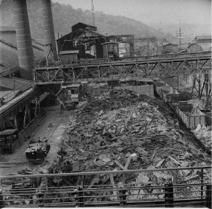 Thale. VEB Eisen- und Hüttenwerke Thale, Stahlwerk. Schrottplatz mit Lagerfläche, Güterzug auf dem Werkbahngleis und Brückenkran