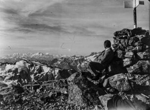 Auf dem Schwarzhorn : Ein Mann sitzt auf dem Gipfel des Schwarzhorns und schaut in die Berge u.a. auf die Berge der Berninagruppe.