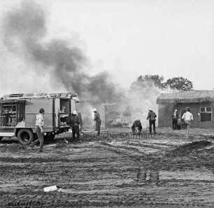 Stemwarde: Kreisfeuerwehrverbandstag: Löschübung: hinten Feuerwehrmänner beim Löschen von Tankstelle und Wohnhaus: links Löschwagen: davor Feuerwehrmänner beim Verlegen der Wasserschläuche