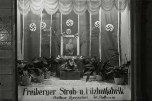 Roßwein. Schaufensterdekoration der Filiale der Freiberger Stroh- u. Filzhutfabrik zu Adolf Hitlers 50. Geburtstag am 20.4.1939 mit Hitlerportrait und Hakenkreuzfahnen