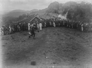 Ankunft der Karawane : Ankunft der Karawane vor einer Siedlung. Die Mitglieder haben sich auf der Straße aufgestellt und schauen in Richtung des Fotografen
