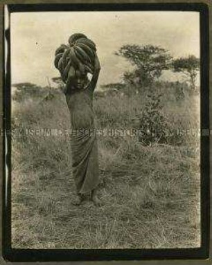 Afrikanisches Kind beim Transport von Bananen