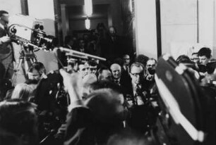 Die Staatssekretäre Egon Bahr (verdeckt) und Michael Kohl nach der Unterzeichnung den Verkehrsvertrags zwischen der DDR und der BRD umringt von Journalisten