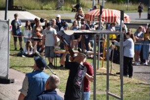 Bad Oldesloe: Kindervogelschießen: Exer: Teilnehmer beim Anlegen, daneben Aufsichtsperson, die auf Vogel zeigt: im Hintergrund Schießstand der Mädchen und Zuschauer: 13. Juli 2023