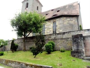 Ansicht von Norden mit Kirche (im Kern spätromanisch) über Kirchhofmauer sowie vorgelagerter (niedrigerer) Zwingermauer (jeweils Wehrgang mit Steinbrüstung im 19 Jh abgetragen)