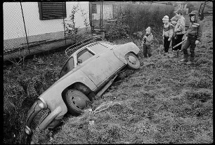 Kinder an einem Autowrack im Graben