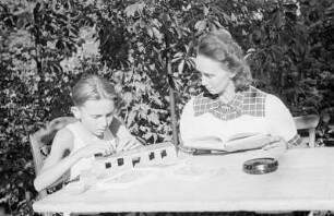 Porträt von Walter Dehmel mit Familie im Garten : Frau Dehmel mit Enkelsohn beim Spielen an einem Tisch