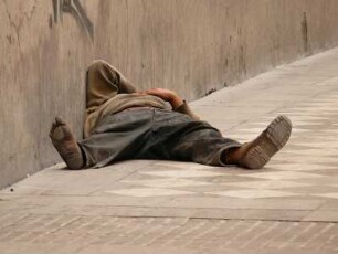 Armer Mann schläft am hellen Tage auf der Straße vor einer Kirche in Granada, Andalusien, Spanien