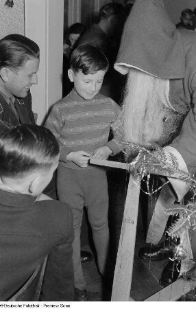 Weihnachtsmann, einem kleinen Jungen einen Roller überreichend
