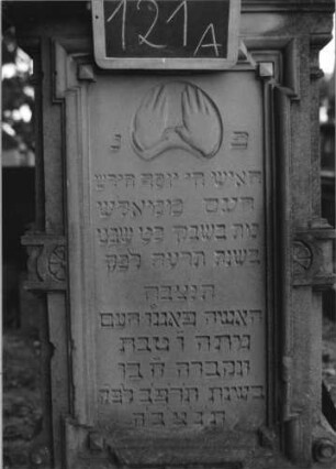 Grabstein 121 (Index: 100080486) Material: Sandstein Zustand: chluß beschädigt Maße HxBxT: 192x57x27 cm Beschreibung: stele, getreppt. Sockel, eingezog. Rundbogenabschl. m. Verdach. , Schrift eingetieft#Abs Symbolik: segnende Hände, Muschel im Abschluß: Grabstein 121A