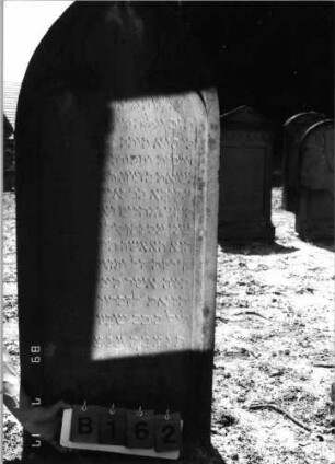 Grabstein 162 (Index: 99798012) Material: Sandstein, rot Zustand: leicht verwittert Maße HxBxT: 142x60x17 cm Beschreibung: Stele, Spitzbogenabschluß Symbolik: Maßwerk: Grabstein 162B
