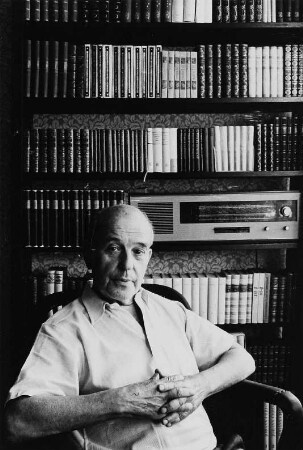 Der Schriftsteller Wieland Herzfelde in seiner Wohnung in Berlin-Weißensee, vor einem Bücherregal sitzend