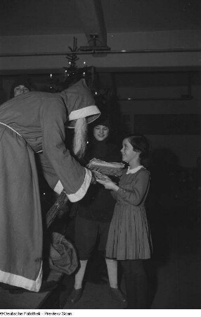 Weihnachtsmann, einem Mädchen ein Geschenk überreichend