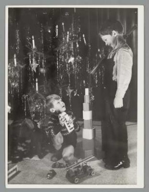 Zwei Jungen mit Spielzeug vor einem Weihnachtsbaum