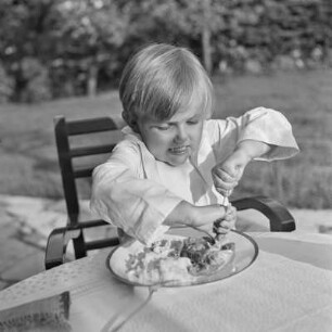 Junge isst auf einer Terrasse