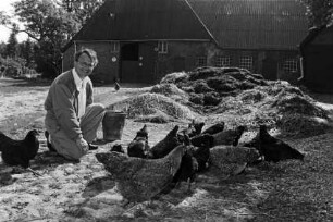 Hof von Günther Fielmann: Besitzer hockend neben Misthaufen und Hühnern: im Hintergrund Scheune