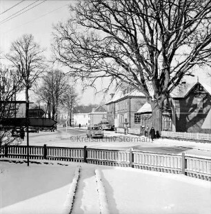 Kirchenstraße / Poststraße mit Pkw und Fahrradfahrer und Fußgängern: links Abzweigung Rausdorfer Straße: im Hintergrund rechts Genossenschaftsmeierei, davor Lkw: Winter