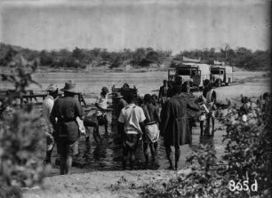 Autos in Landschaft : Expeditionsteilnehmer und Automobile in einer Landschaft mit einem Gewässer