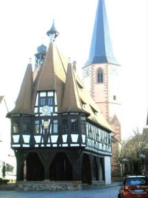 Stadtbild-Rathaus-Ansicht von Westen mit Fachwerkobergeschoß und Eckerkern über offener Erdgeschoßhalle sowie Stadtkirche in Übersicht