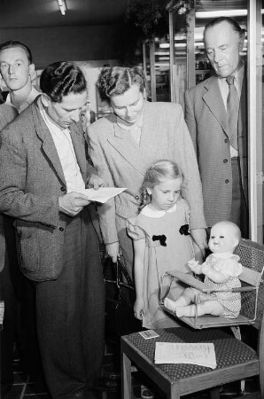 Besucher der Leipziger Herbstmesse 1955 betrachten eine Hochstuhlkonstruktion für Kleinkinder