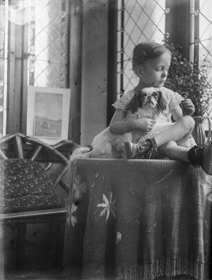 Friederike Apel : Dresden, Regerstraße 22. Die Tochter der Fotografin mit einem kleinen Hund auf einem Tisch sitzend