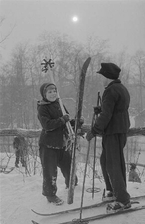 Leipzig, Johannapark. Kinder beim Ski- und Schlittenfahren, zwei Kinder mit Skiern im Gespräch