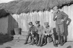 Zweiter Weltkrieg. Zur Einquartierung. Sowjetunion. Vier Angehörige der deutschen Wehrmacht vor einer Bauernhütte