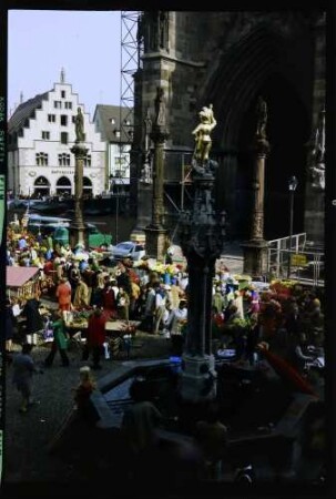 Freiburg: Münsterbrunnen von der Eisdiele, mit Markt und Kornhaus