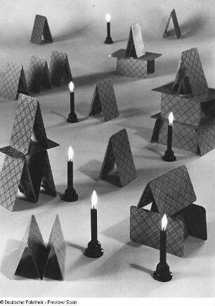 Arrangement aus Kartenhäusern und Kerzen