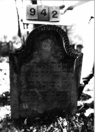 Grabstein 942 (Index: 99753162) Material: Sandstein Zustand: abgeblättert/verwittert Maße HxBxT: 88x56x7 cm Beschreibung: Stele, Konvexbogenabschluß, Schriftfeld eingetieft Symbolik: Scheibenfries: Grabstein 942