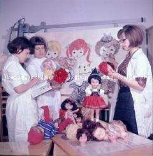 Mitarbeiterinnen des VEB Puppenfabrik Waltershausen studieren Puppenfrisuren und -kleidung