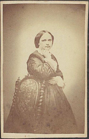 Bertha Cornelius, stehend, an einen Stuhl gelehnt