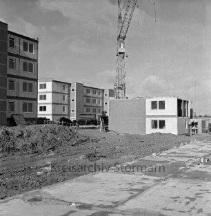 Lottbek: Neubausiedlung: Wohnungsbau: vorn Fundament: links Erdhaufen und Reste von Baumaterial: dahinter Wohnblocks vor Fertigstellung: in der Mitte Baukran: links davor Wohnblock im Bau