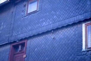 Detail einer Schieferfassade: am Übergang zum OG eine Zierkante