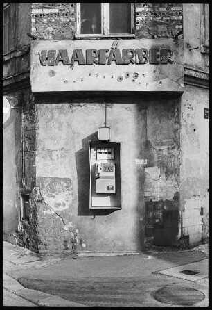 Hausfassade an einer Straßenecke mit Inschrift "Haarfärber" und Telefon