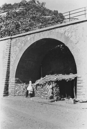 Hütte unter einem Viaduktbogen : Blick von einer Straße auf einen Viaduktbogen, in dem sich Personen eine Hütte errichtet haben