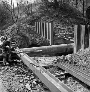 Bahnstrecke zwischen Hamburg und Lübeck: Auetal: Erneuerung der Brücke über die Aue: Spundwände: Arbeiter schweißt Rahmen für neuen Stahlbeton-Durchlass: Aue (Mühlenbach) fließt in Rohr