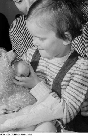 Ein Kleinkind mit Stoffbären auf der Weihnachtsfeier für Kinder der Betriebsangehörigen der HO Lebensmittel Leipzig West