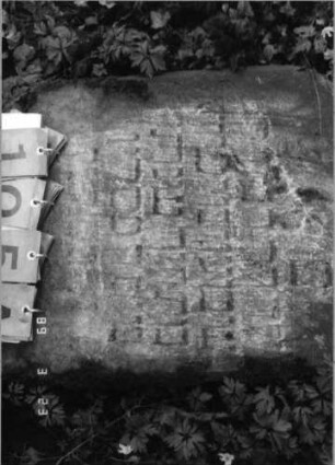 Grabstein 105 (Index: 99792190) Material: Sandstein Zustand: verwittert mit Textverlust, Stele liegend Maße HxBxT: 70x48x10 cm Beschreibung: Stele, Segmentbogenabschluß Besonderheit: Kindergrab: Grabstein 105A