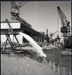 Abpumpen von Wasser aus der Baugrube eines Großbunkers für deutsche U-Boote in einem Hafen an der französischen Atlantikküste, im Hintergrund ist bereits ein fertiggestellter Bunker