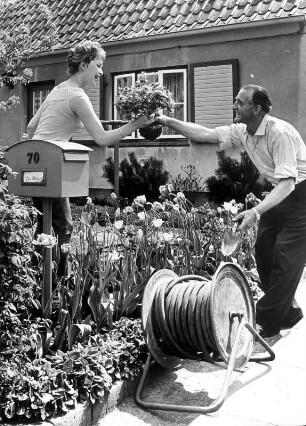 Er überreicht der schönen Nachbarin Blumen. Werbefoto für einen Prospekt der Hamburger Gaswerke (GW)