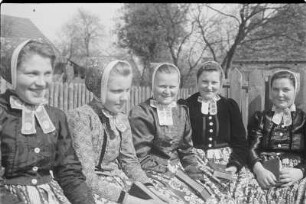 Mädchen in Schleifer Tracht aus Rohne auf der Singebank in Rohne. : Holcy w Slepjanskej drasće z Rowneho na spěwarskej ławcy w Rownom.