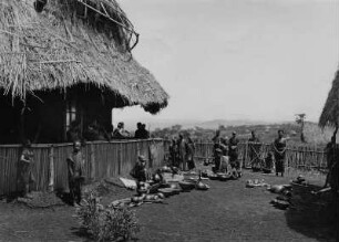 Männer und Frauen mit ethnographischen Gegenständen auf der Mission.