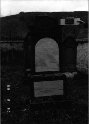 Grabstein 33 (Index: 99798347) Material: Sandstein, Schriftplatten Marmor Zustand: gut, Teil des Bogenabschlusses fehlt Maße HxBxT: 185x58x20 cm Beschreibung: Stele mit eingezogenem Rundbogenabschluß, Schriftfeld mit Rundbogenabschluß, Sockel Symbolik: Kanne in Schale Steinmetz: Daniel Bauman: Grabstein 33