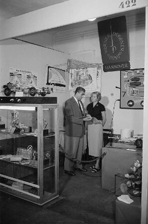 Ein Mann und eine Frau am Stand der Werner Degener Lehrmittel GmbH auf der Leipziger Herbstmesse 1955