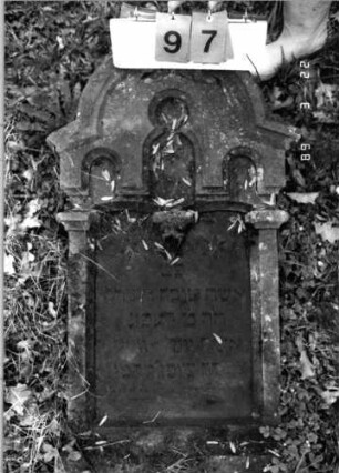 Grabstein 97 (Index: 99792174) Material: Sandstein, Marmorplatte Zustand: leicht verwittert, liegende Stele Maße HxBxT: 105x61x13 cm Beschreibung: ädikulaartige Stele mit Pfeilern, eingezogener Rundbogenabschluß, Schriftplatte Symbolik: gestelztes Rundbogenfries, Blüten: Grabstein 97