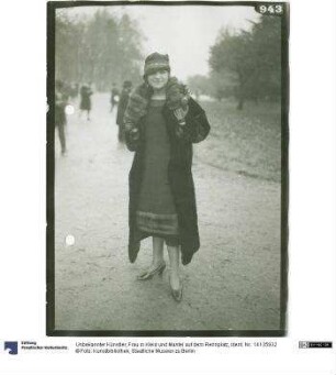 Frau in Kleid und Mantel auf dem Rennplatz