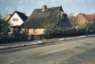 Alte Landstraße 18: giebelständige Fachwerkkate mit Reetdach: Traufseite: Straßenfront mit Eingangstür und großer Gaube [umgebaut]