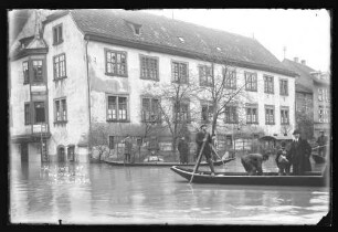 Hochwasser Ecke Brückengasse/Lindenstraße vor Chorstift-Drogerie und Brunnen sowie Personen auf Schelchen, darauf Schriftzug "Hochwasser in Wertheim (vermutlich Jan. 1920)"