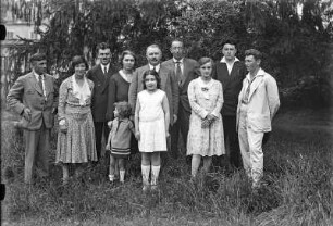 Gruppenbildnis festlich gekleideter Personen (wohl während einer Familienfeier), aufgenommen in einem Garten